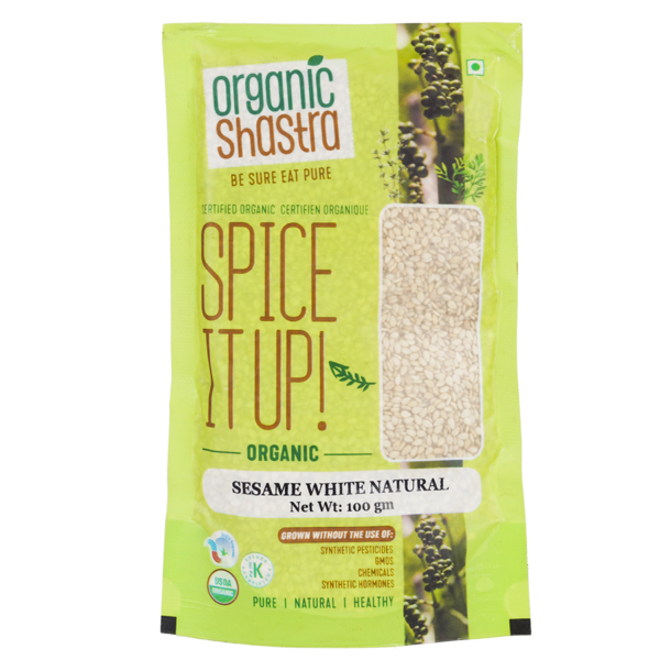 Organic Shastra Sesame White Natural 100 gm package with green and yellow design, featuring 'Spice It Up! Organic Sesame White Natural' text, and certifications for being organic, free from synthetic pesticides, GMOs, chemicals, and synthetic hormones