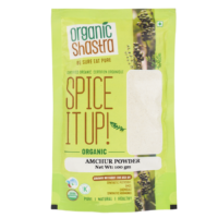 Organic Shastra Amchur Powder 100 gm packaging with green and yellow design, featuring the text 'Spice It Up! Organic Amchur Powder', 'Be Sure Eat Pure', and certifications for being organic, free from synthetic pesticides, GMOs, chemicals, and synthetic hormones