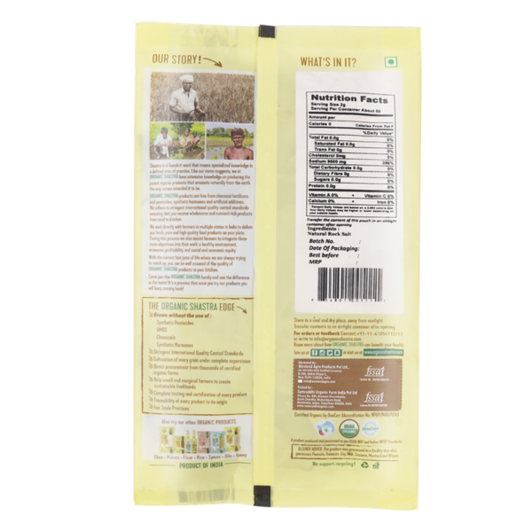 Organic Shastra Natural Rock Salt Pink Powder, 1 kg pack. The packaging is yellow with green accents, featuring the text 'Spice It Up!' and 'Certified Organic'. The product is free from synthetic pesticides, GMOs, chemicals, and synthetic hormones